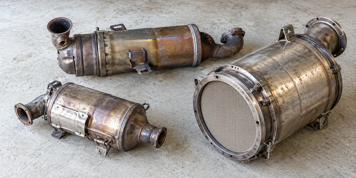 Three removed DPF filters for a car, 4WD and truck, with the larger truck filter showing its honeycomb core
